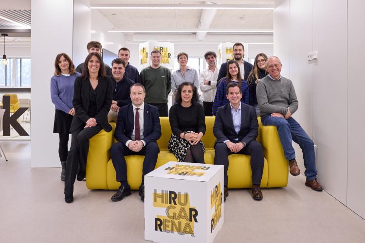 Grupo de personas posando en un sofá con cubo delante con un logo