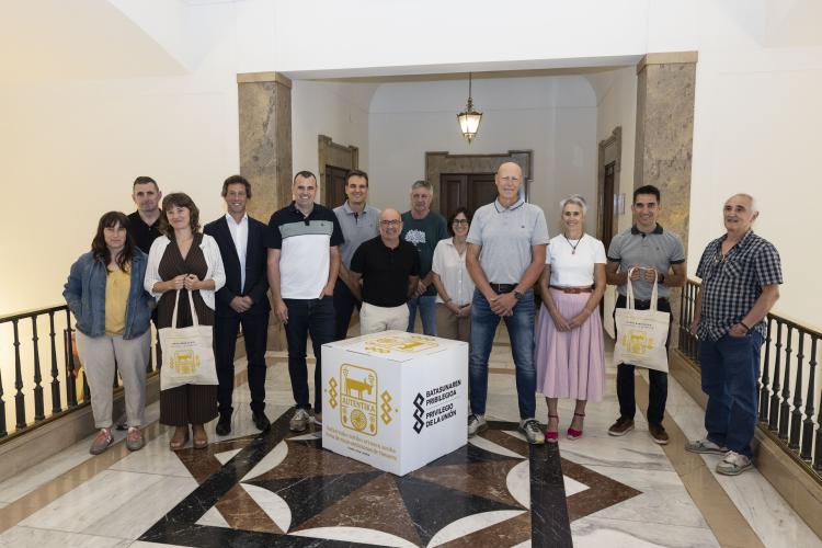 Foto de un grupo de personas detrás de un cubo con el logo de la feria y dos de ellos sosteniendo bolsas de la misma
