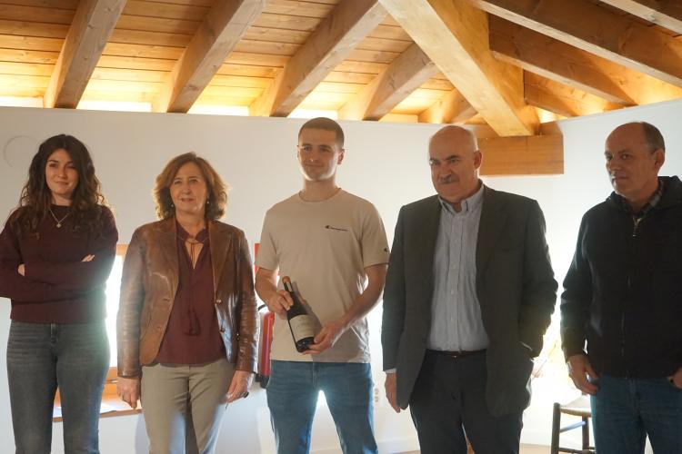4 personas posando junto con una botella de vino