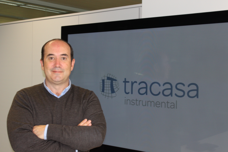 Imagen de César Arriaga junto a una pantalla de televisión en la que si visualiza el logo de Tracasa Instrumental
