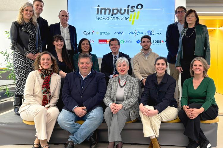 Foto grupal de varias personas sentadas y de pie delante del logo de la iniciativa