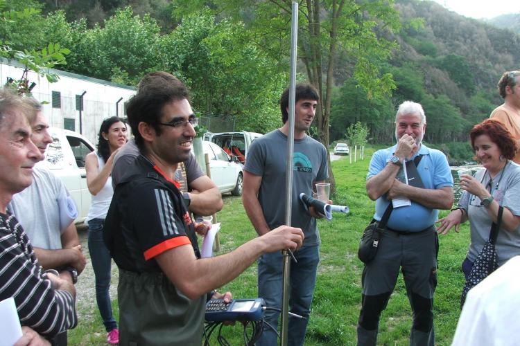 Varias personas atienden las explicaciones de un técnico en una visita de campo. Uno de ellos sostiene en la mano un aparato de medición.