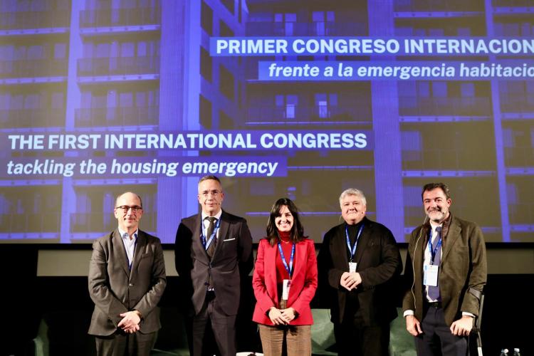 Fotografía de cinco participantes en el congreso mirando a cámara en fila con el nombre del congreso detrás de sí. Dos hombres a mano izquierda, una mujer en el centro y otros dos hombre a mano derecha.
