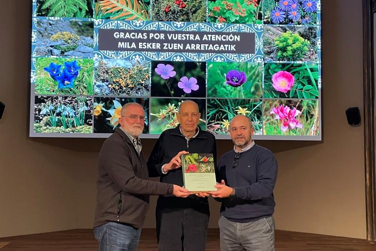 Fotografía donde se ve a tres hombres mirando a cámara y sosteniendo conjuntamente un ejemplar del atlas presentado